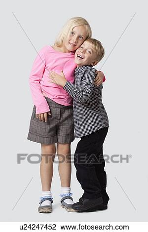 Portrait of cheerful young boy embracing sister over white background View Large Photo Image Stock Image - Portrait of cheerful young boy embracing sister over white background. Fotosearch