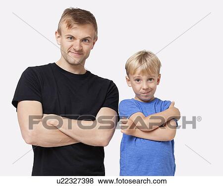 Stock Photo - Portrait of happy father and son in casuals with arms crossed over white background. Fotosearch