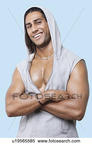 Portrait of happy young muscular man wearing hooded jacket standing against colored background View Large Photo Image Stock Photography - Portrait of happy young muscular man wearing hooded jacket standing against colored background. Fotosearch