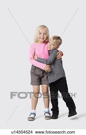 Portrait of happy young siblings hugging over white background View Large Photo Image Picture - Portrait of happy young siblings hugging over white background. Fotosearch