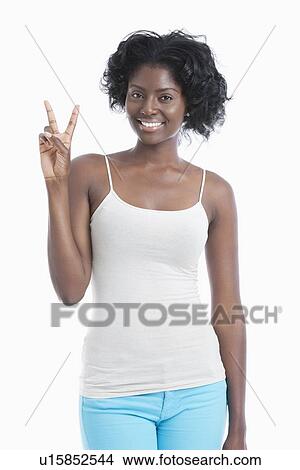 Picture - Portrait of happy young woman gesturing victory sign over white background. Fotosearch