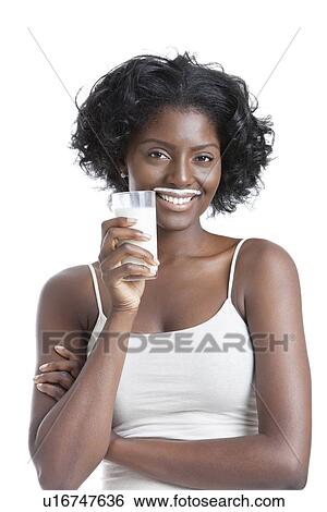 Stock Photograph - Portrait of happy young woman with milk moustache holding glass of milk. Fotosearch