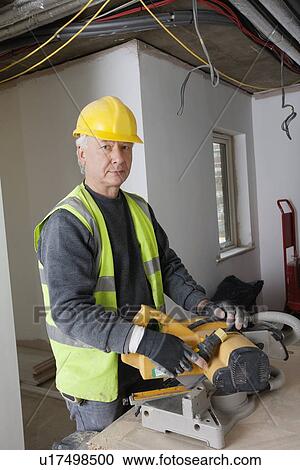 Stock Image - Portrait of middle-aged worker at construction site. Fotosearch