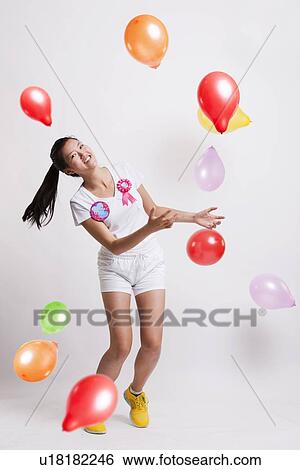 Portrait of playful young woman with multicolored balloons celebrating her birthday against white background View Large Photo Image Stock Photograph - Portrait of playful young woman with multicolored balloons celebrating her birthday against white background. Fotosearch