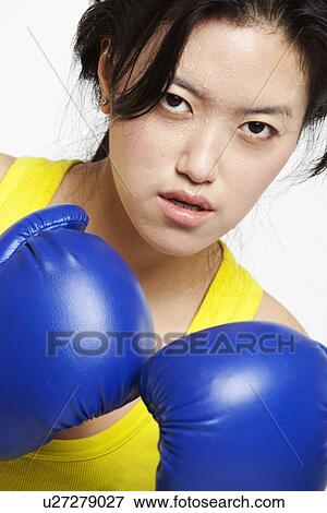 Portrait of serious Asian woman wearing boxing gloves against white background View Large Photo Image Stock Photo - Portrait of serious Asian woman wearing boxing gloves against white background. Fotosearch