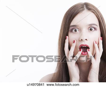 Portrait of shocked young woman with hands on face against white background View Large Photo Image Stock Image - Portrait of shocked young woman with hands on face against white background. Fotosearch