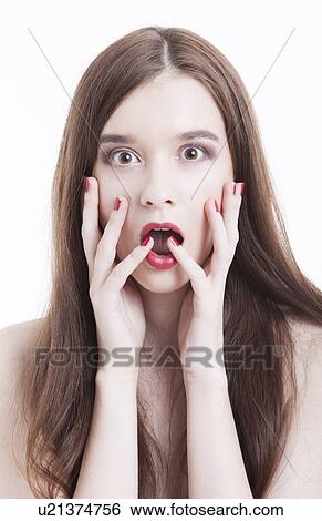 Portrait of shocked young woman with hands on face against white background View Large Photo Image Stock Photograph - Portrait of shocked young woman with hands on face against white background. Fotosearch
