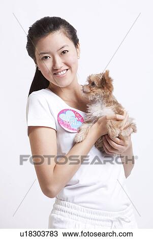 Portrait of smiling Asian woman with a puppy against white background View Large Photo Image Stock Image - Portrait of smiling Asian woman with a puppy against white background. Fotosearch