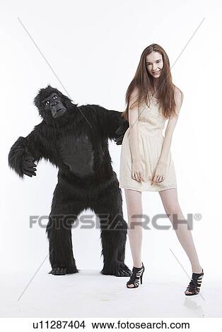 Portrait of smiling young woman with man in gorilla costume against white background View Large Photo Image Picture - Portrait of smiling young woman with man in gorilla costume against white background. Fotosearch