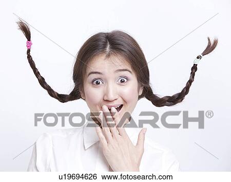 Portrait of surprised young woman with braids curling upwards against white background View Large Photo Image Stock Photograph - Portrait of surprised young woman with braids curling upwards against white background. Fotosearch