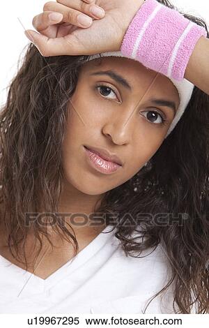 Portrait of tired young woman with hand on head against white background View Large Photo Image Stock Photography - Portrait of tired young woman with hand on head against white background. Fotosearch