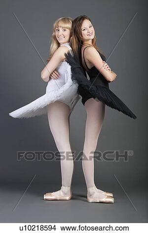 Portrait of two young female ballet dancers standing back to back over grey background View Large Photo Image Picture - Portrait of two young female ballet dancers standing back to back over grey background. Fotosearch