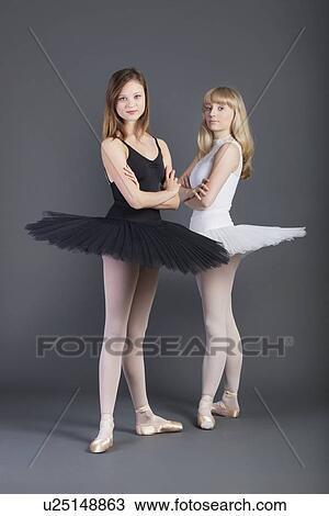 Portrait of two young female ballet dancers with arms crossed standing over grey background View Large Photo Image Stock Image - Portrait of two young female ballet dancers with arms crossed standing over grey background. Fotosearch