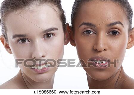 Portrait of two young women with fake teeth against white background View Large Photo Image Stock Image - Portrait of two young women with fake teeth against white background. Fotosearch