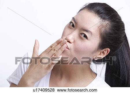 Portrait of young Asian woman blowing kiss against white background View Large Photo Image Stock Photo - Portrait of young Asian woman blowing kiss against white background. Fotosearch