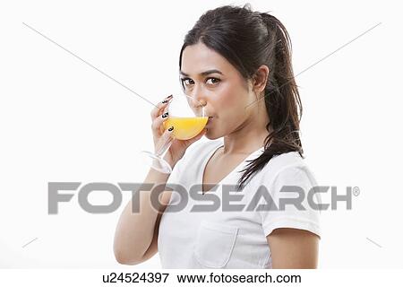 Stock Photo - Portrait of young Asian woman drinking orange juice over white background. Fotosearch