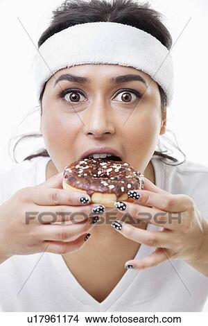 Portrait of young Asian woman eating donut over white background View Large Photo Image Picture - Portrait of young Asian woman eating donut over white background. Fotosearch