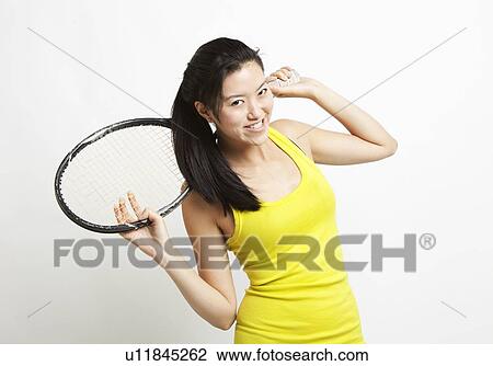 Portrait of young Asian woman holding tennis racket over her shoulder against white background View Large Photo Image Stock Image - Portrait of young Asian woman holding tennis racket over her shoulder against white background. Fotosearch