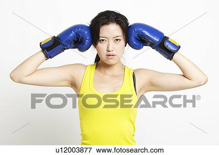 Portrait of young Asian woman in yellow tank top wearing boxing gloves against white background View Large Photo Image Stock Photo - Portrait of young Asian woman in yellow tank top wearing boxing gloves against white background. Fotosearch