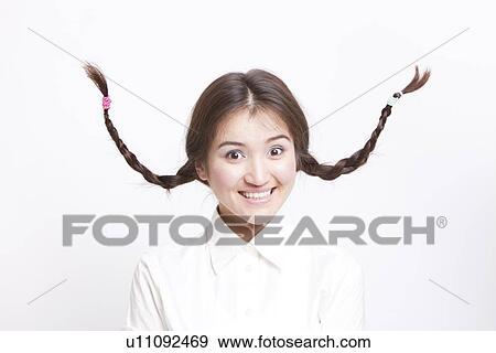 Portrait of young Asian woman with braids curling upwards against white background View Large Photo Image Stock Photo - Portrait of young Asian woman with braids curling upwards against white background. Fotosearch