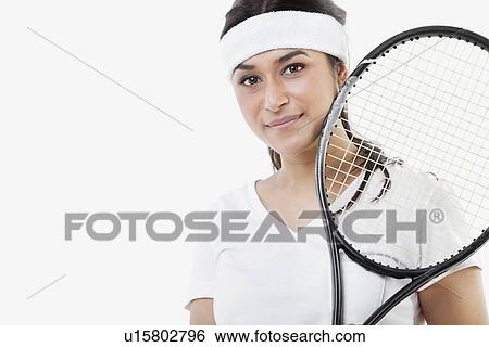 Stock Photograph - Portrait of young Asian woman with tennis racket against white background. Fotosearch