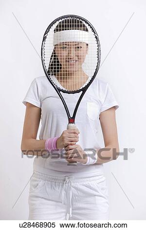 Portrait of young female tennis player holding racket in front of her face against white background View Large Photo Image Stock Photography - Portrait of young female tennis player holding racket in front of her face against white background. Fotosearch