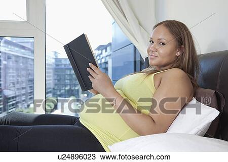 Portrait of young pregnant woman with book relaxing on bed at home View Large Photo Image Stock Image - Portrait of young pregnant woman with book relaxing on bed at home. Fotosearch