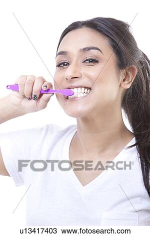 Portrait of young woman brushing teeth over white background View Large Photo Image Stock Image - Portrait of young woman brushing teeth over white background. Fotosearch
