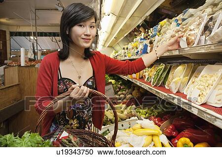Portrait of young woman choosing mushroom package in market View Large Photo Image Stock Image - Portrait of young woman choosing mushroom package in market. Fotosearch