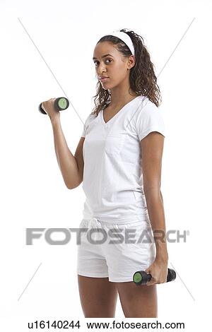 Portrait of young woman exercising with dumbbells against white background View Large Photo Image Picture - Portrait of young woman exercising with dumbbells against white background. Fotosearch