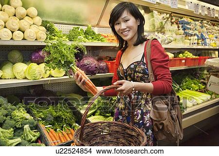 Picture - Portrait of young woman shopping for vegetables in farmer's market. Fotosearch