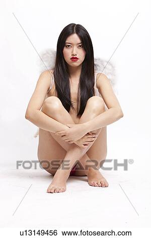 Portrait of young woman with angel wings sitting on floor against white background View Large Photo Image Stock Photograph - Portrait of young woman with angel wings sitting on floor against white background. Fotosearch