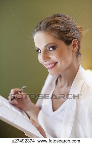 Portrait of young woman writing notes on spiral notebook View Large Photo Image Picture - Portrait of young woman writing notes on spiral notebook. Fotosearch