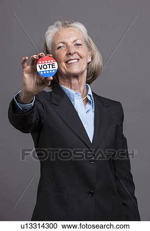 Senior businesswoman holding Vote Badge on grey background View Large Photo Image Stock Image - Senior businesswoman holding Vote Badge on grey background. Fotosearch