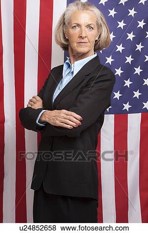 Senior businesswoman with arms folded standing infront of an American flag View Large Photo Image Stock Photo - Senior businesswoman with arms folded standing infront of an American flag. Fotosearch