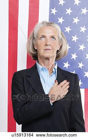 Senior businesswoman with hand over heart against American flag View Large Photo Image Picture - Senior businesswoman with hand over heart against American flag. Fotosearch