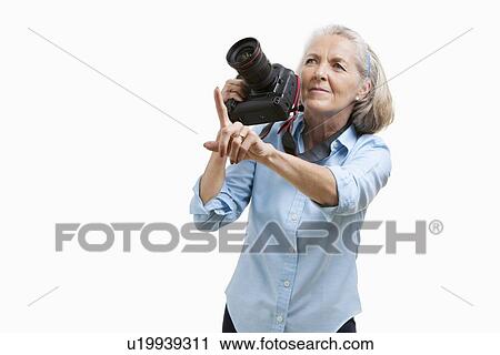 Senior female photographer with camera gesturing against white background View Large Photo Image Stock Image - Senior female photographer with camera gesturing against white background. Fotosearch