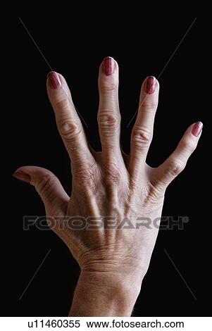 Stock Photography - Senior woman's hand with red nail polish against black background. Fotosearch