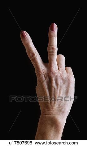 Senior woman's hands gesturing peace sign against black background View Large Photo Image Stock Photo - Senior woman's hands gesturing peace sign against black background. Fotosearch