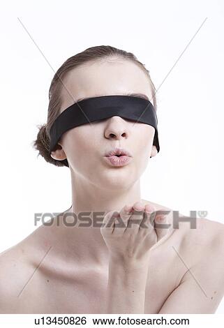Stock Photograph - Shirtless young woman with blindfold blowing a kiss against white background. Fotosearch
