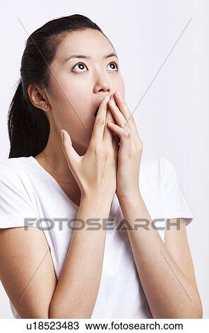 Shocked young woman with hands over mouth against white background View Large Photo Image Stock Image - Shocked young woman with hands over mouth against white background. Fotosearch
