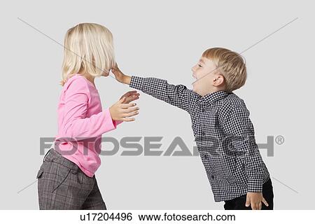 Stock Photograph - Side view of playful young boy and girl over white background. Fotosearch