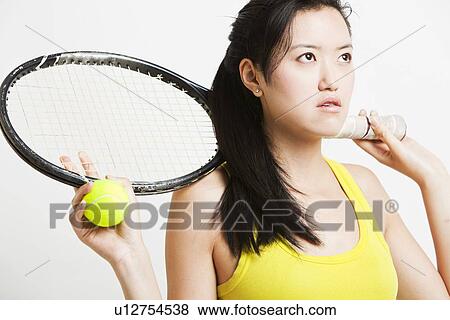 Thoughtful young woman holding tennis racket and ball over white background View Large Photo Image Stock Photo - Thoughtful young woman holding tennis racket and ball over white background. Fotosearch