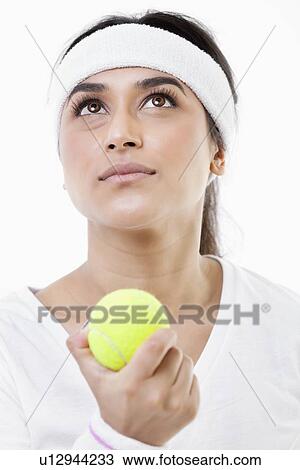 Stock Image - Young ambitious female tennis player looking up over white background. Fotosearch