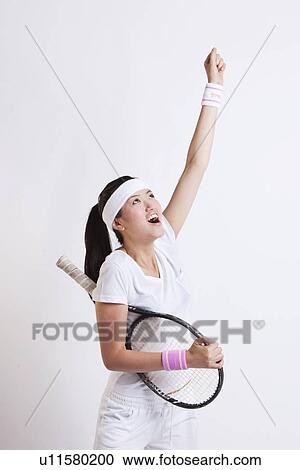 Stock Image - Young Asian female tennis player celebrating her success against white background. Fotosearch