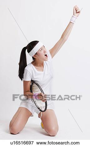 Young Asian female tennis player celebrating her success against white background View Large Photo Image Stock Photo - Young Asian female tennis player celebrating her success against white background. Fotosearch
