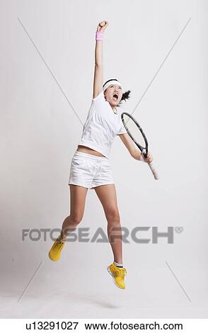 Young Asian female tennis player with racket jumping in excitement against white background View Large Photo Image Stock Photo - Young Asian female tennis player with racket jumping in excitement against white background. Fotosearch