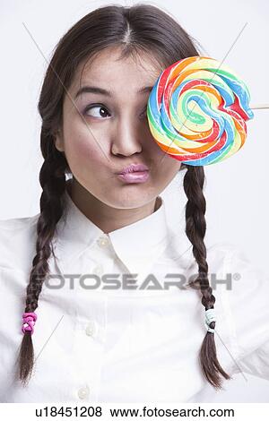Young Asian woman holding a multicolored lollipop against white background View Large Photo Image Stock Photo - Young Asian woman holding a multicolored lollipop against white background. Fotosearch