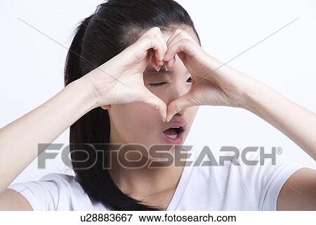 Young Asian woman making heart shape with hands against white background View Large Photo Image Stock Photo - Young Asian woman making heart shape with hands against white background. Fotosearch