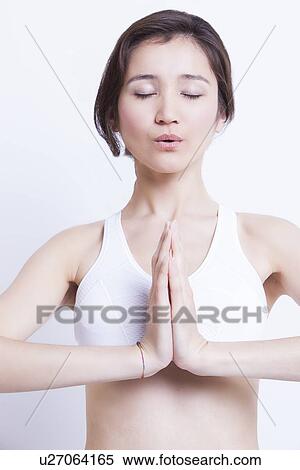 Young Asian woman meditating with hands clasped against white background View Large Photo Image Stock Photography - Young Asian woman meditating with hands clasped against white background. Fotosearch
